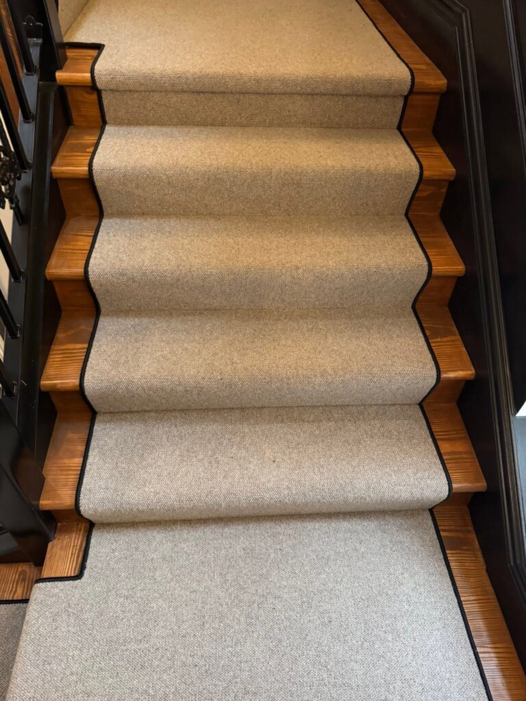 Wool stair runner with black border fitted on wooden stairs by Cuttin Edge Carpets, Halifax